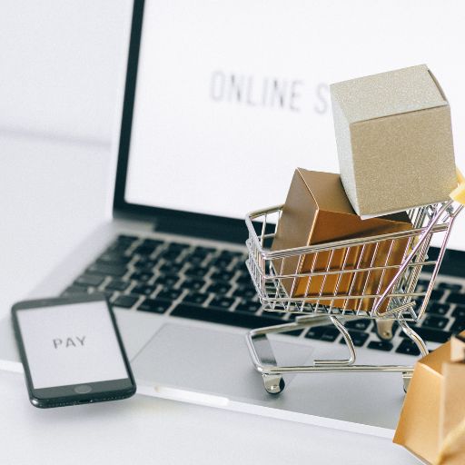 Mini cart with packages on laptop showing online store and pay option, symbolizing Shopify ecommerce website services in Kochi