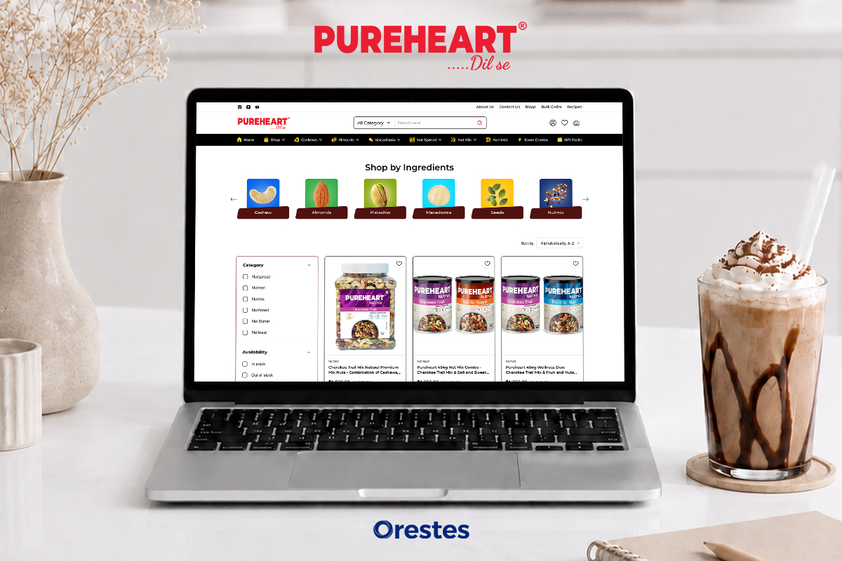 Pureheart e-commerce website shop by ingredients page displayed on a laptop mockup, showcasing cashews, almonds, and pistachios in a bright kitchen setting.