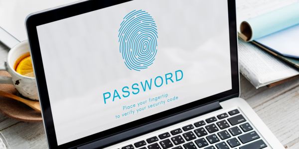 A laptop displaying a fingerprint login screen with the word “PASSWORD,” symbolizing digital security and data protection, representing a modern workspace of an SEO agency in Kochi