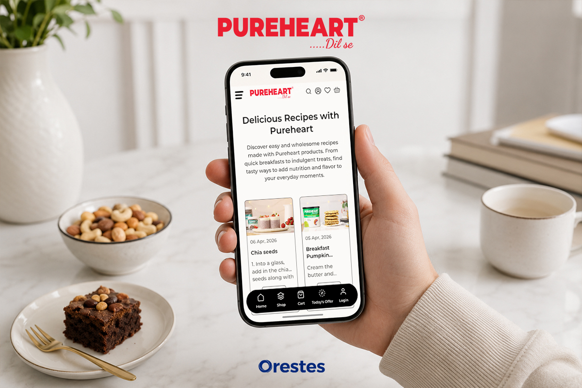 Hand holding a smartphone displaying the Pureheart responsive recipe blog interface featuring healthy snacks and breakfast ideas.