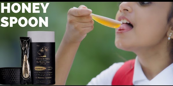 Product advertisement for Thadathil Farm Honey Spoons, showing the black packaging and a single-use honey spoon next to a child tasting golden honey.