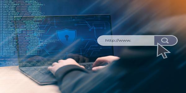 A person typing on a laptop displaying a digital security shield, with programming code and a web search bar overlay symbolizing cybersecurity and online protection.