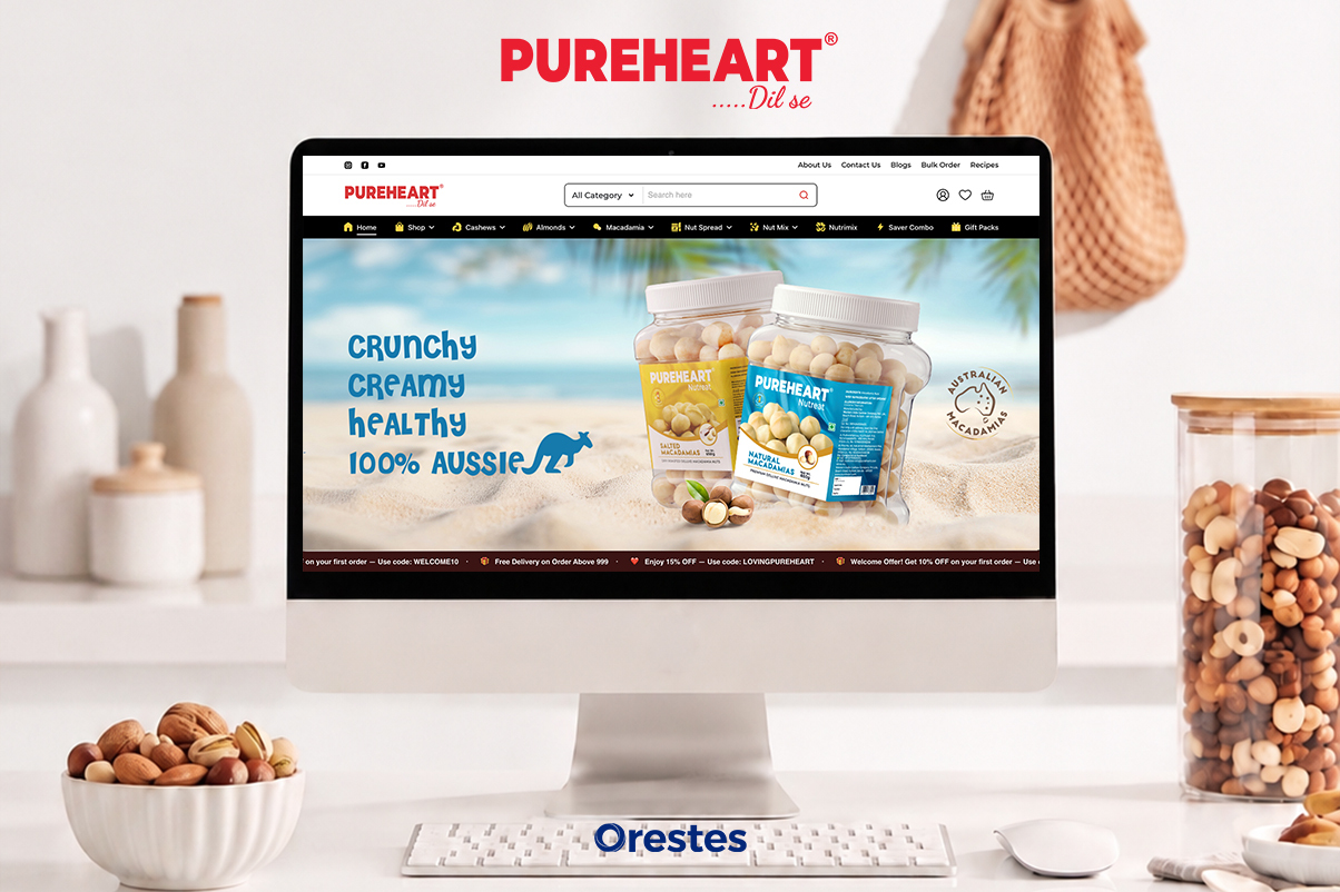 Pureheart website homepage banner featuring Australian Macadamias displayed on a modern desktop computer monitor next to a basket of mixed nuts.