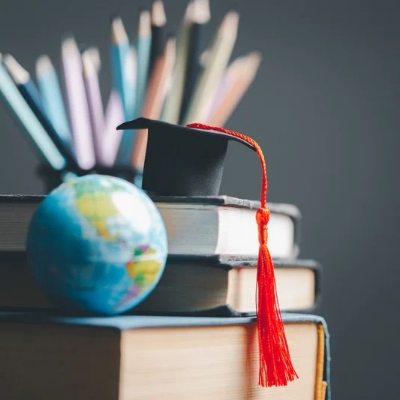 Stack of books with a graduation cap and small globe symbolizing global education and knowledge — creative concept by the best digital marketing company in Kerala for academic brand promotion.