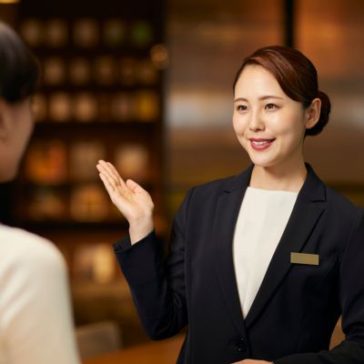 Hotel receptionist greeting a guest with a warm smile, showcasing professional hospitality and brand image enhanced through expert Digital Marketing Services in India.