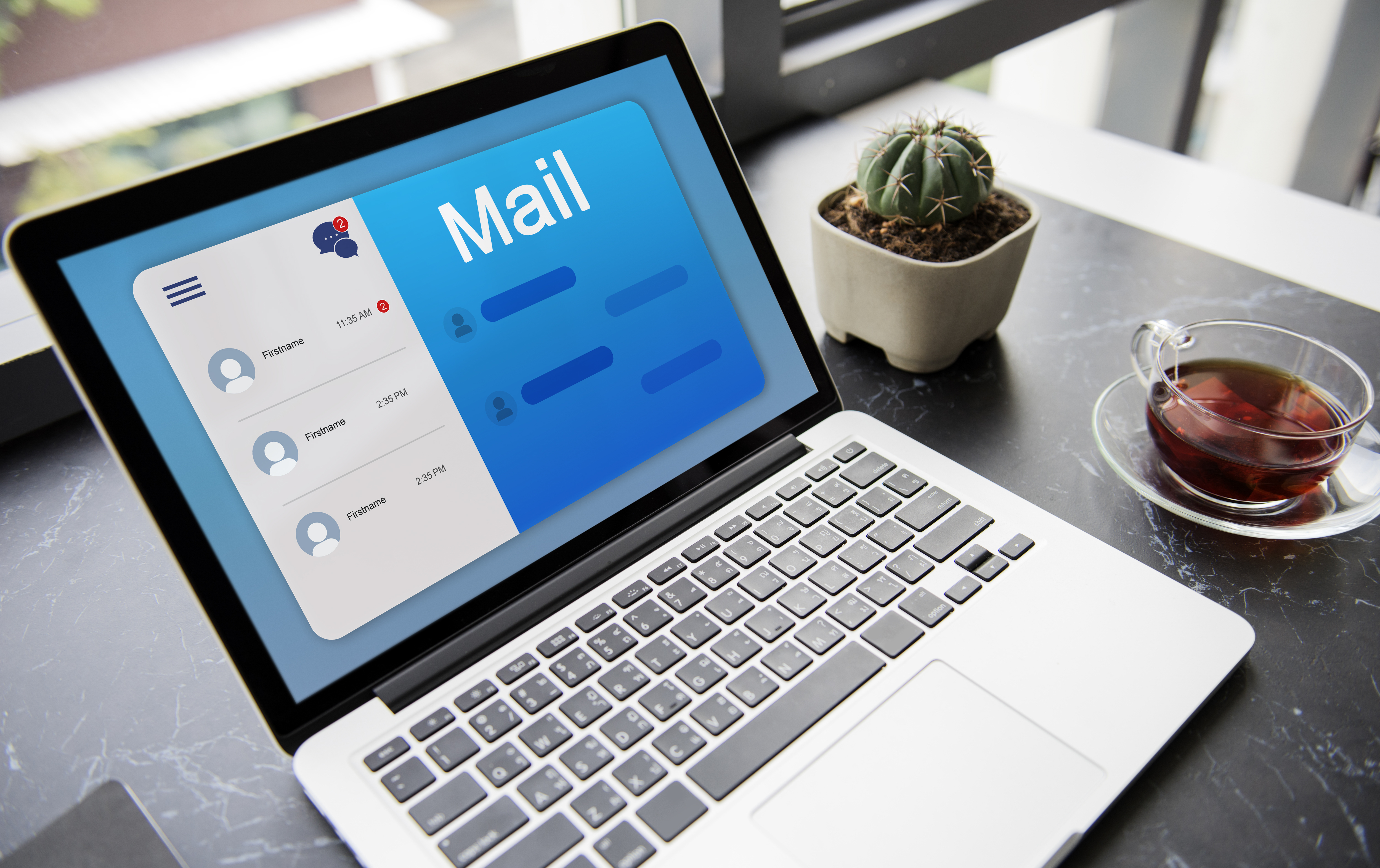 A laptop displaying an email inbox interface beside a cup of tea and a small cactus on a desk, representing a modern digital workspace of an SEO agency in Kochi