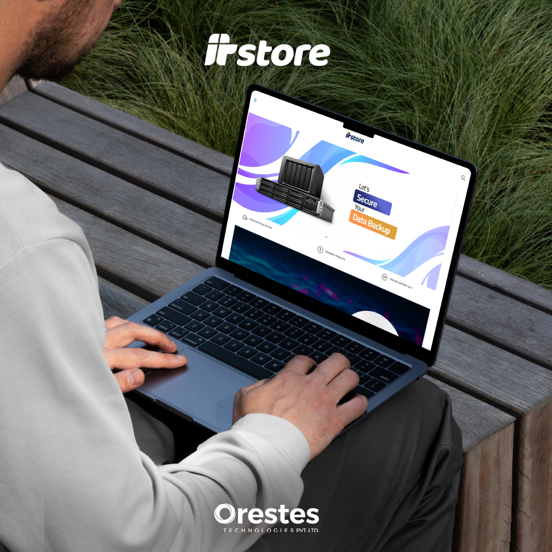 A close-up, over-the-shoulder view of a person using a laptop outdoors on a wooden bench, viewing the ITStore "Secure Your Data Backup" landing page.